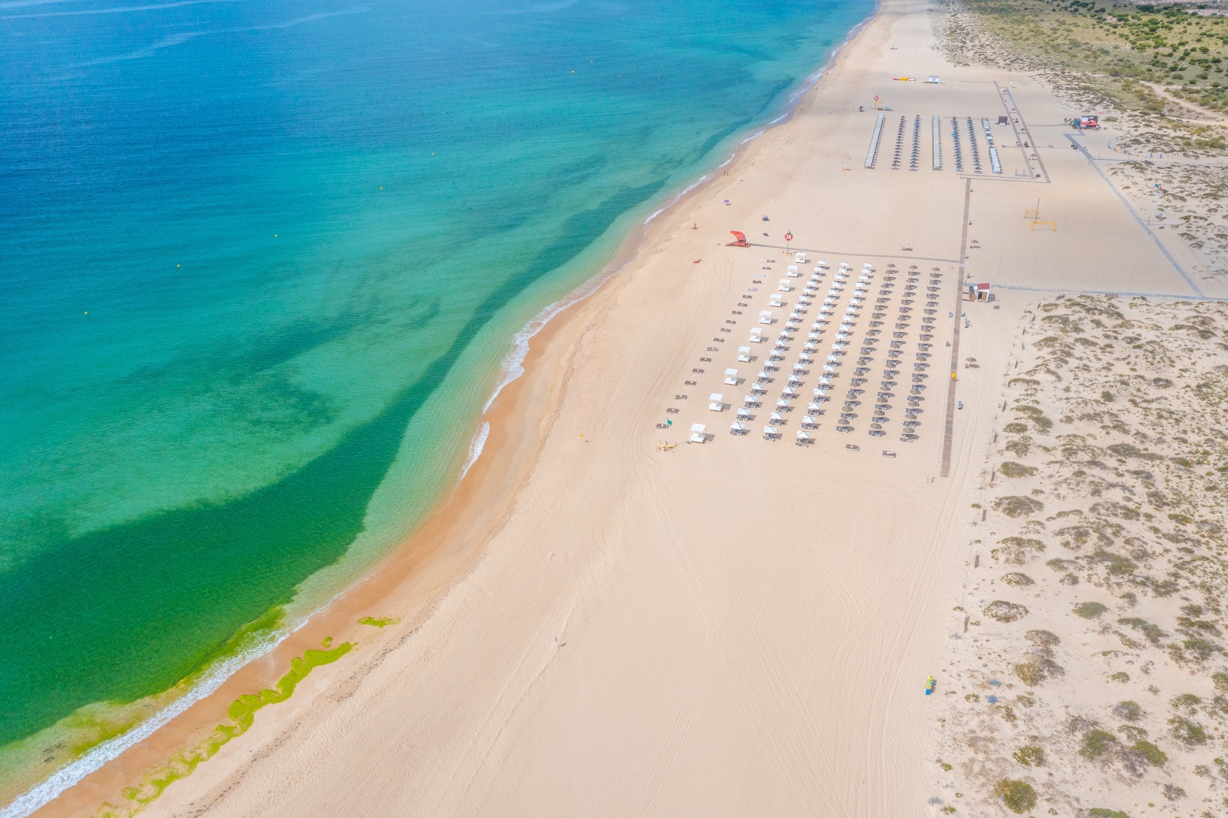 Flot luftfoto af Tavira strand i Algarve Portugal med turkisblåt vand og parasolver
