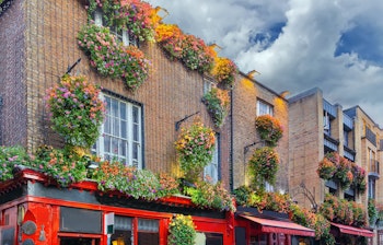 Charmerende farverige bygninger med smukke blomsterdekorationer i Temple Bar-kvarteret, Dublins historiske kulturdistrikt med traditionelle irske pubber