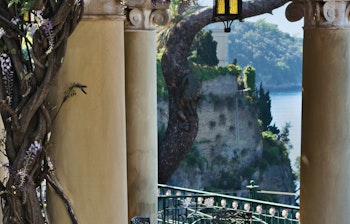 Idyllisk terrasse med blomstrende blaaregn og udsigt over Middelhavet og Sorrento-halvøen i Italien