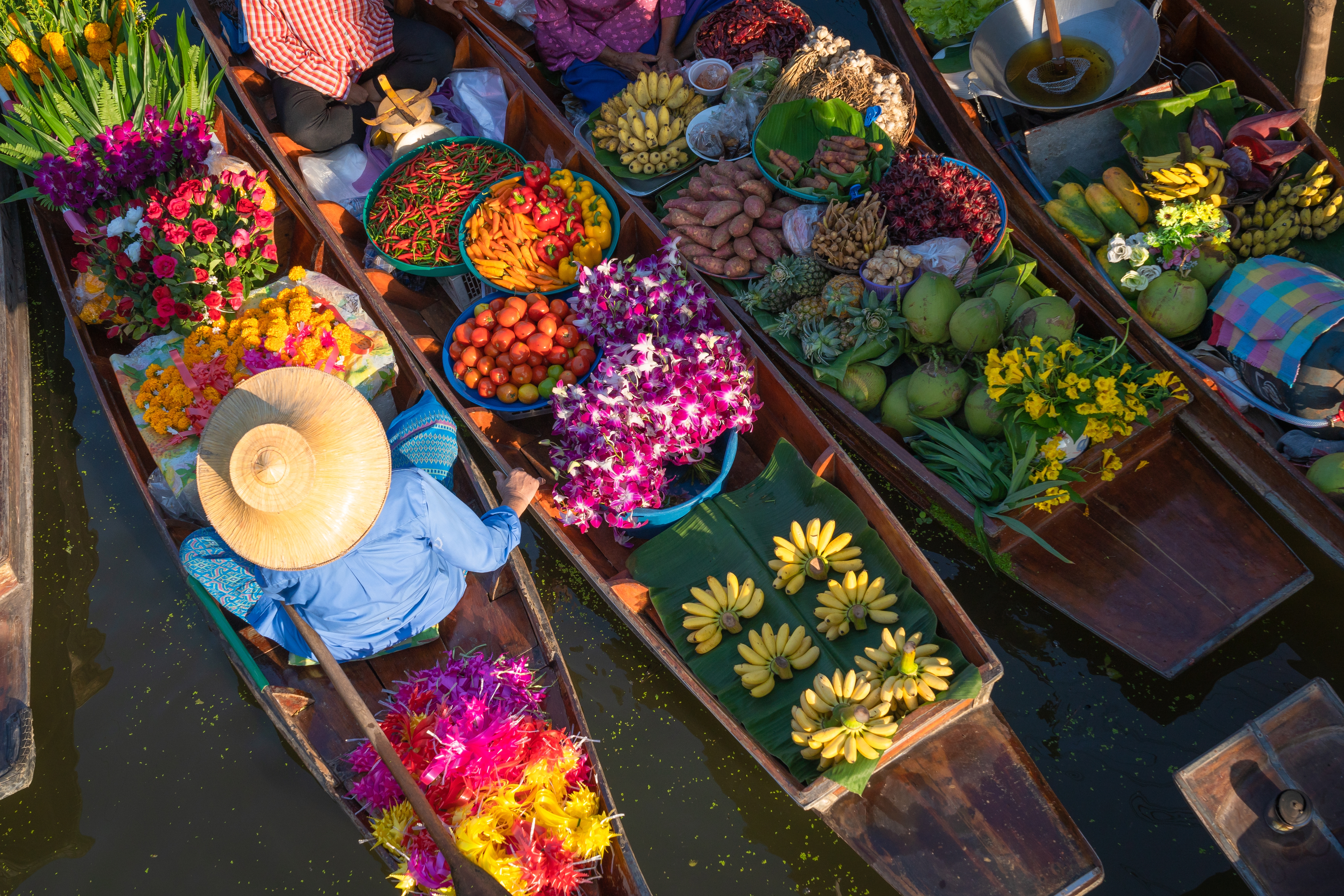 Luftfoto af farverige både på flydende marked i Thailand med frisk frugt og blomster