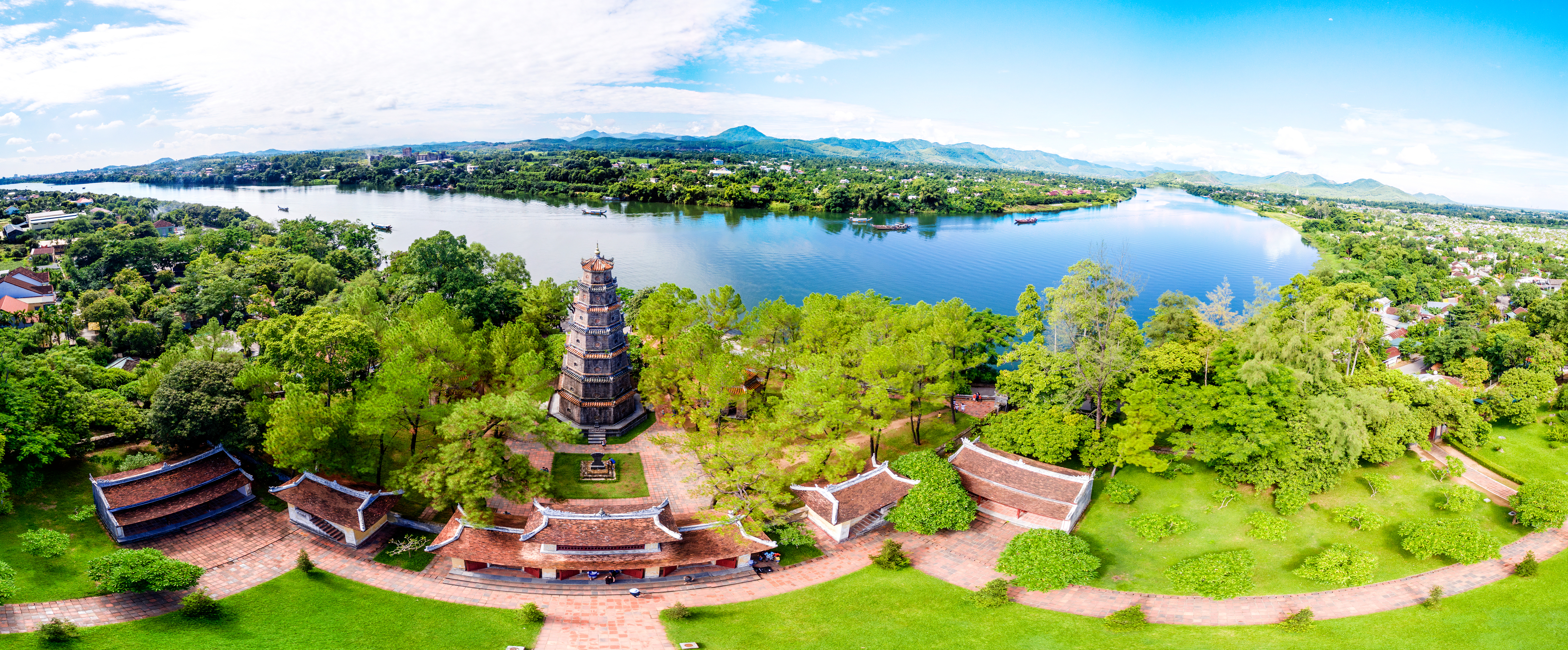 Luftfoto af den historiske Thien Mu Pagoda ved Parfumefloden i Hue, Vietnam, omgivet af frodig grøn natur