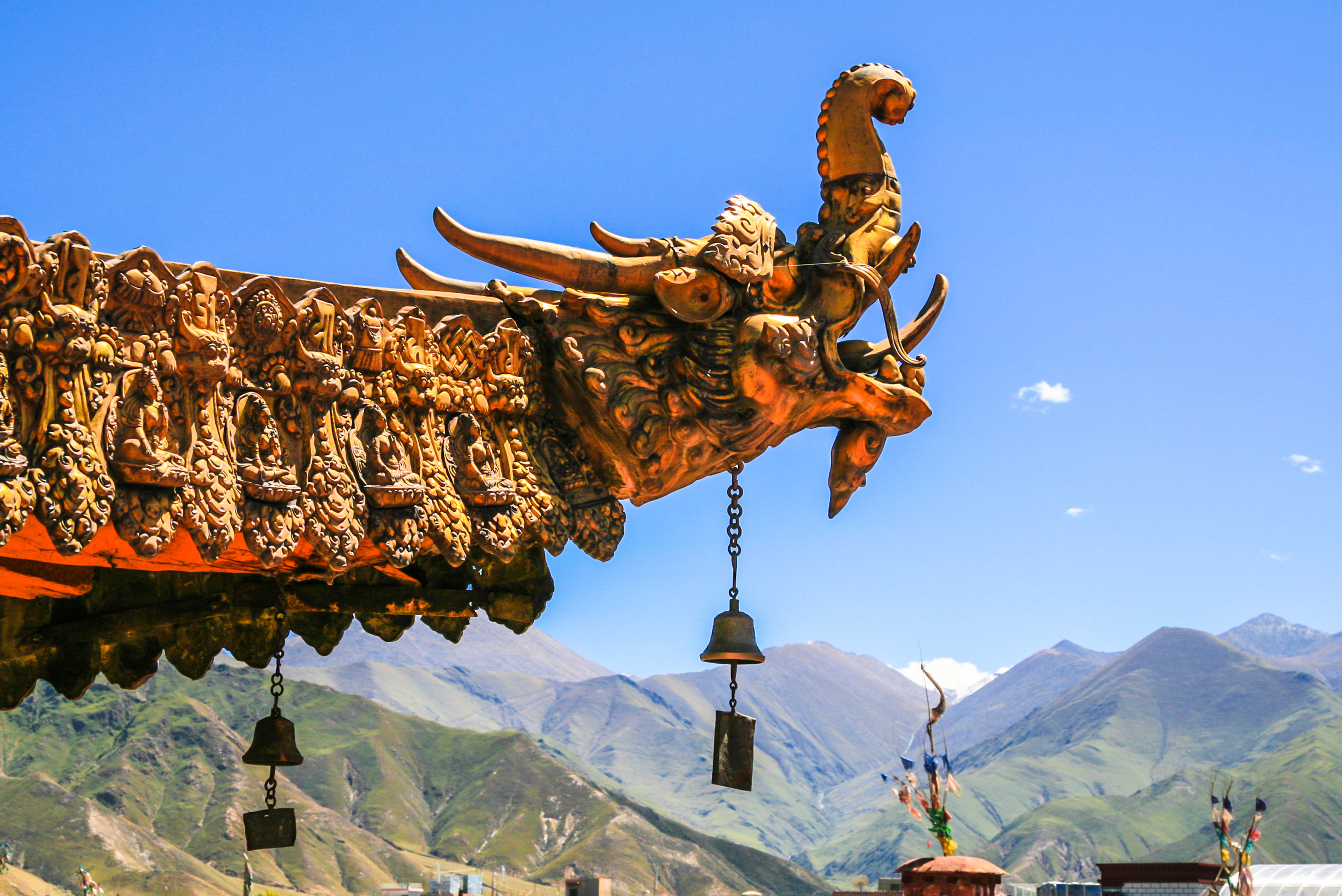 Traditionel tibetansk tempel drageudskæring med bedebjælder mod bjerglandskab i Tibet