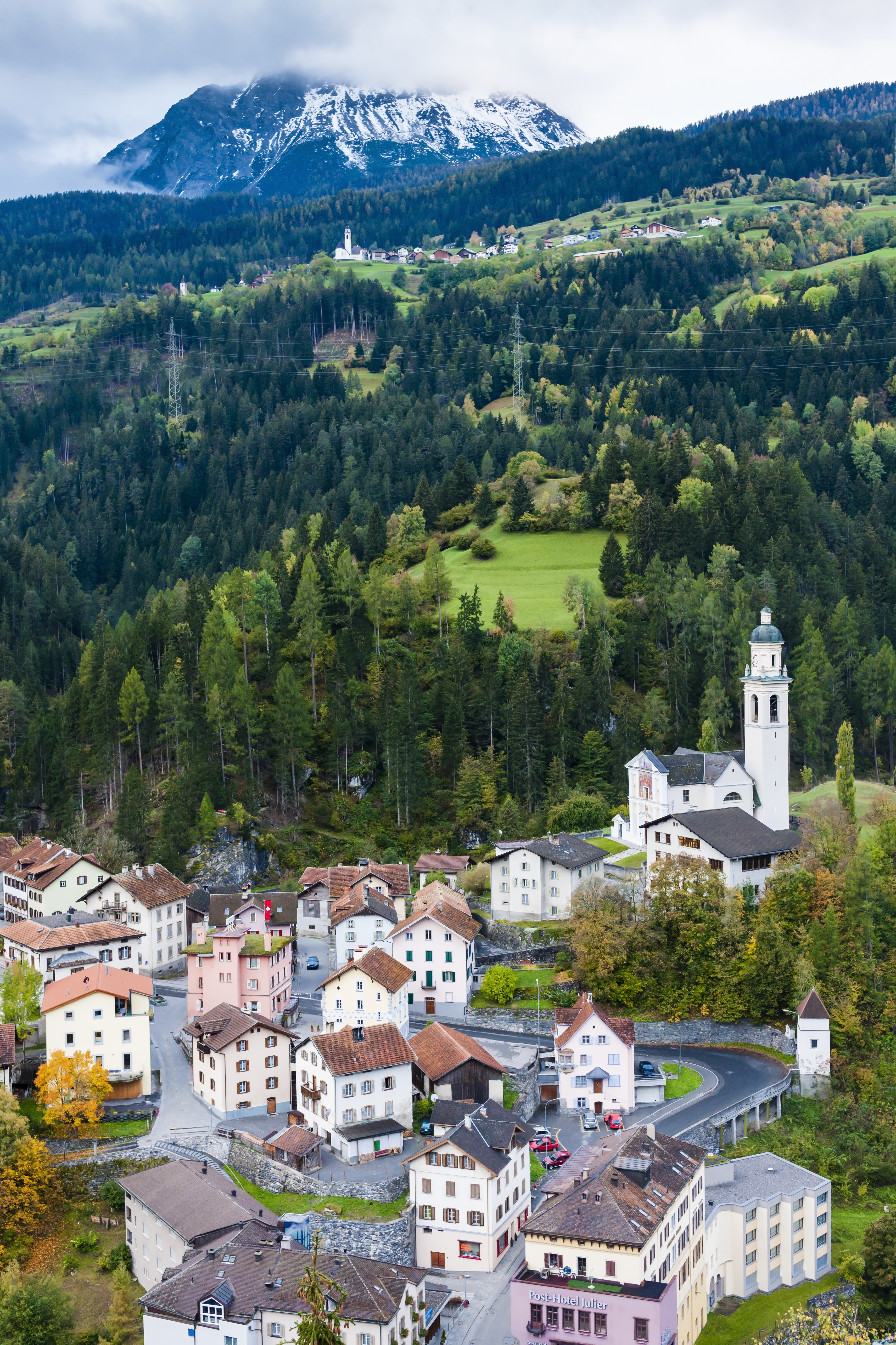 Idyllisk bjerglandsby Tiefencastel med traditionel kirke og arkitektur omgivet af de majestætiske alper i Graubünden, Schweiz