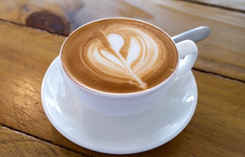 Autentisk Timorese kaffe med latte-kunst serveret på et rustikt træbord i Timor-Leste, en unik kaffeoplevelse fra Sydøstasien