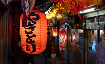 Traditionelle røde japanske lanterner lyser op i Shinjukus livlige natteliv i Tokyo med restauranter og barer i baggrunden