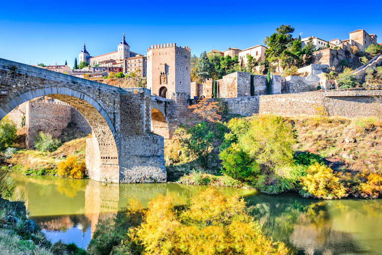 Historisk stenbro og middelalderborg i Toledo Spanien med efteraarsfarver ved Tagus floden