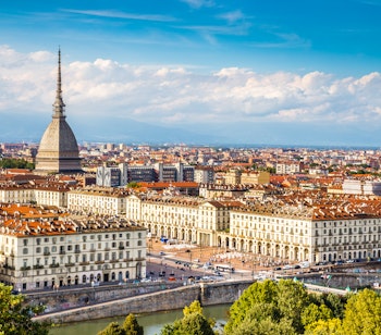 Panoramisk udsigt over Torino bycentrum med det ikoniske Mole Antonelliana tårn omgivet af bjerge under blå himmel i Piemonte, Italien