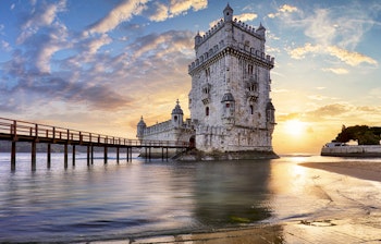 Det historiske Belém-tårn badet i gyldent sollys ved Tagus-flodens bred i Lissabon - et UNESCO verdensarvssted og sidste farvel for opdagelsesrejsende