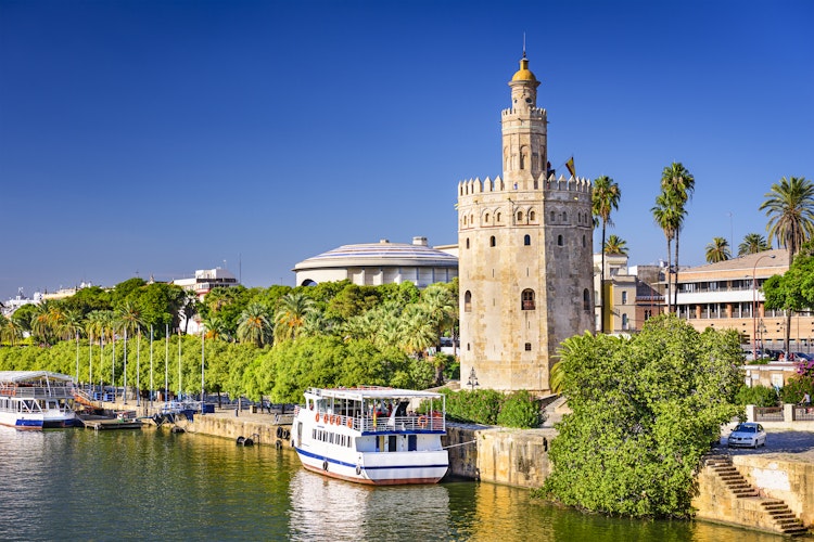 Torre del Oro det gyldne tårn ved Guadalquivir floden i Sevilla Spanien med turistbåde