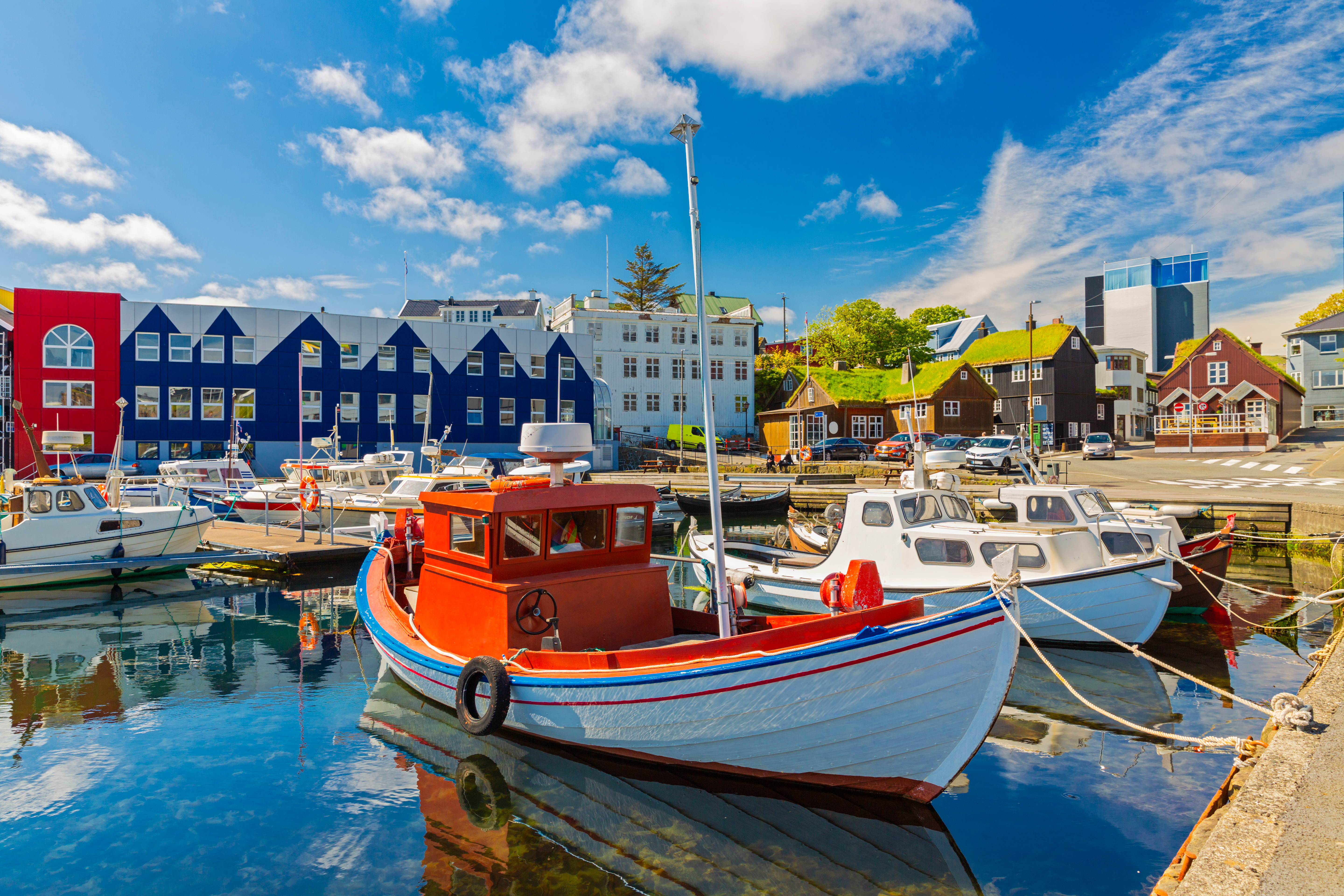 Farverige fiskerbåde i Tórshavns idylliske havn med traditionelle færøske træhuse