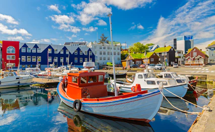 Farverige fiskerbåde i Tórshavns idylliske havn med traditionelle færøske træhuse