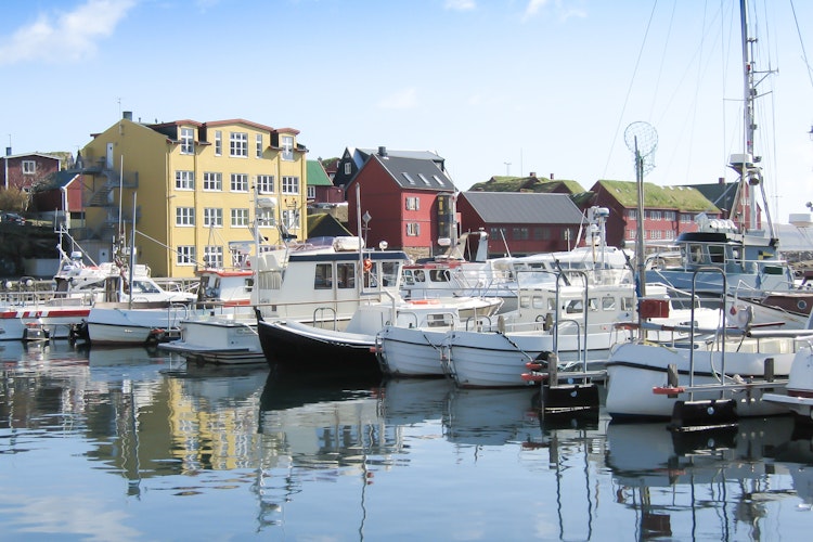 Torshavn Havn på Færøerne med fiskerbåde og lystbåde fortøjet foran de historiske røde regeringsbygninger på Tinganes-halvøen