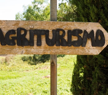 Rustikt træskilt for agriturismo i det smukke toscanske landskab, der viser vej til autentisk italiensk bondegårdsophold