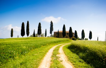 Charmerende landsted omgivet af cyprestræer i Toscanas bakkede landskab ved solnedgang