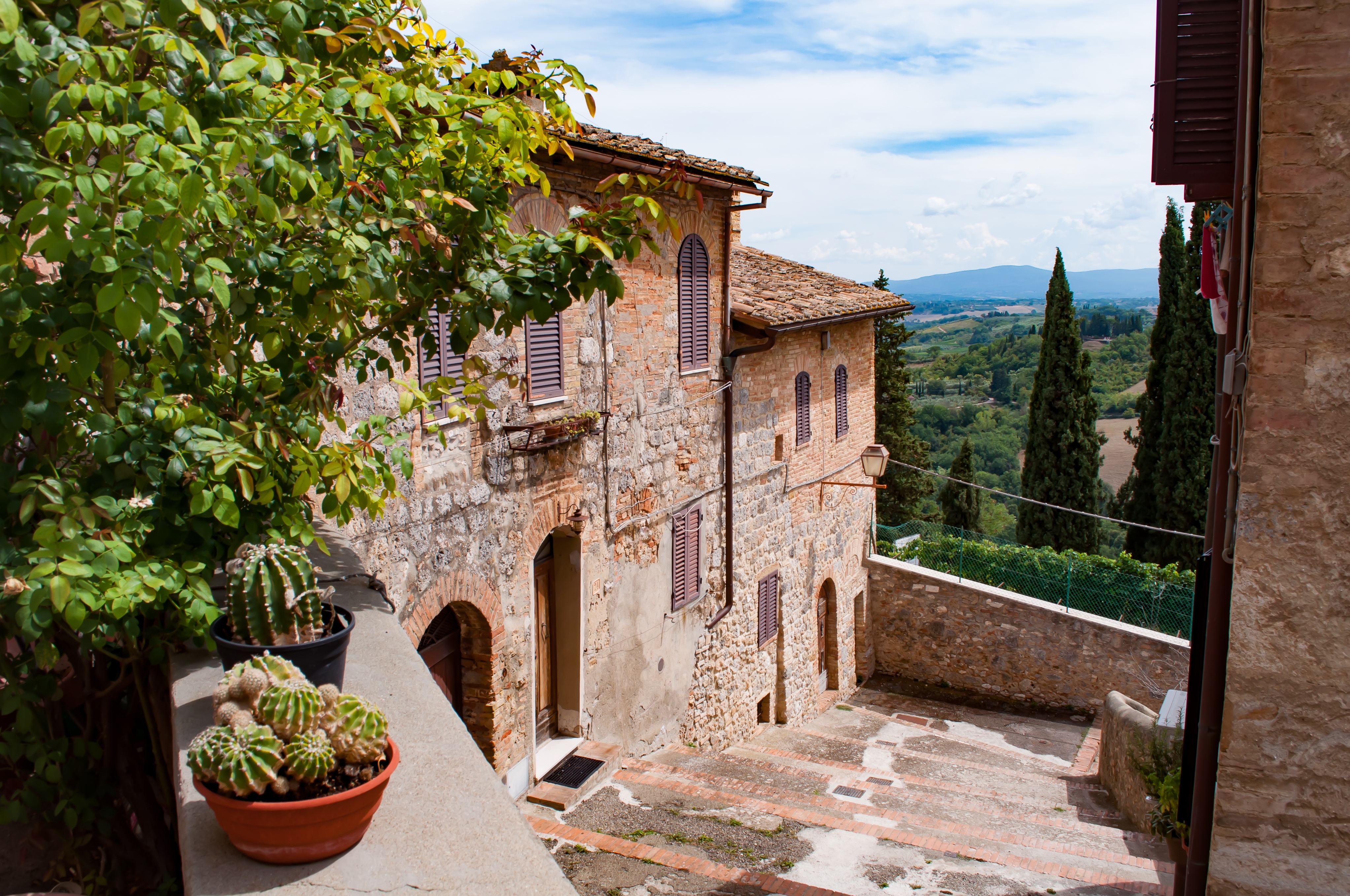 Malerisk toskansk landskab med vinmarker og olivenlunde under San Gimignano, som viser de bølgende bakker i det toskanske landområde