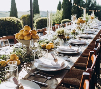 Smukt dækket langbord pyntet med citroner og urter i haven til en charmerende villa i Toscana, perfekt til bryllupsfejring