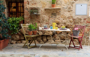 Charmerende udendørs cafe terrasse med farverige stole og stenmur i Toscana Italien