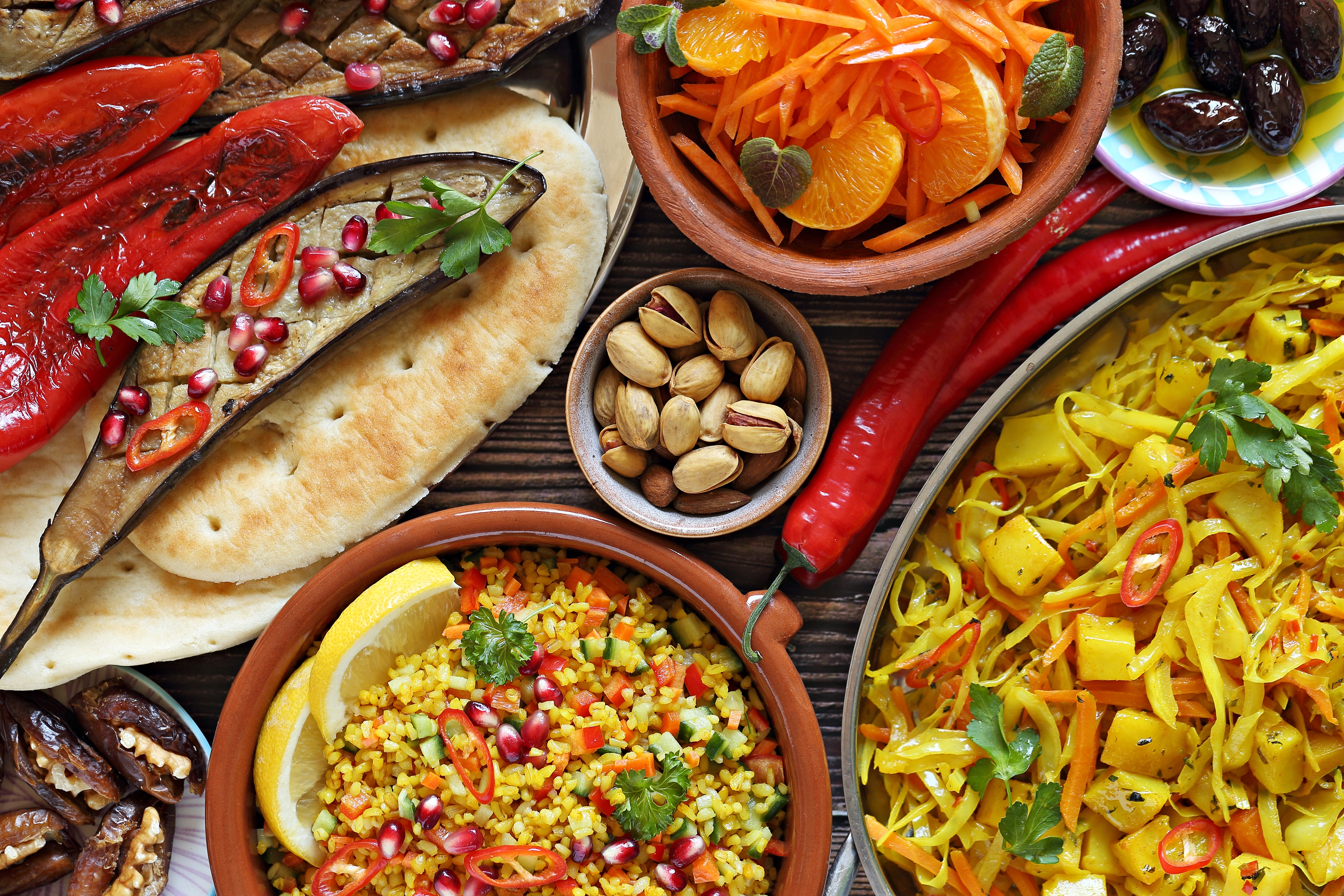 Farverig buffet med traditionelle afrikanske retter, fladbrød, grøntsagssalater og grillede grøntsager serveret på et rustikt træbord