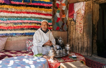 Ældre berberisk mand tilbereder traditionel te på terrassen af sit hjem i Marokko, et eksempel på autentisk arabisk gæstfrihed