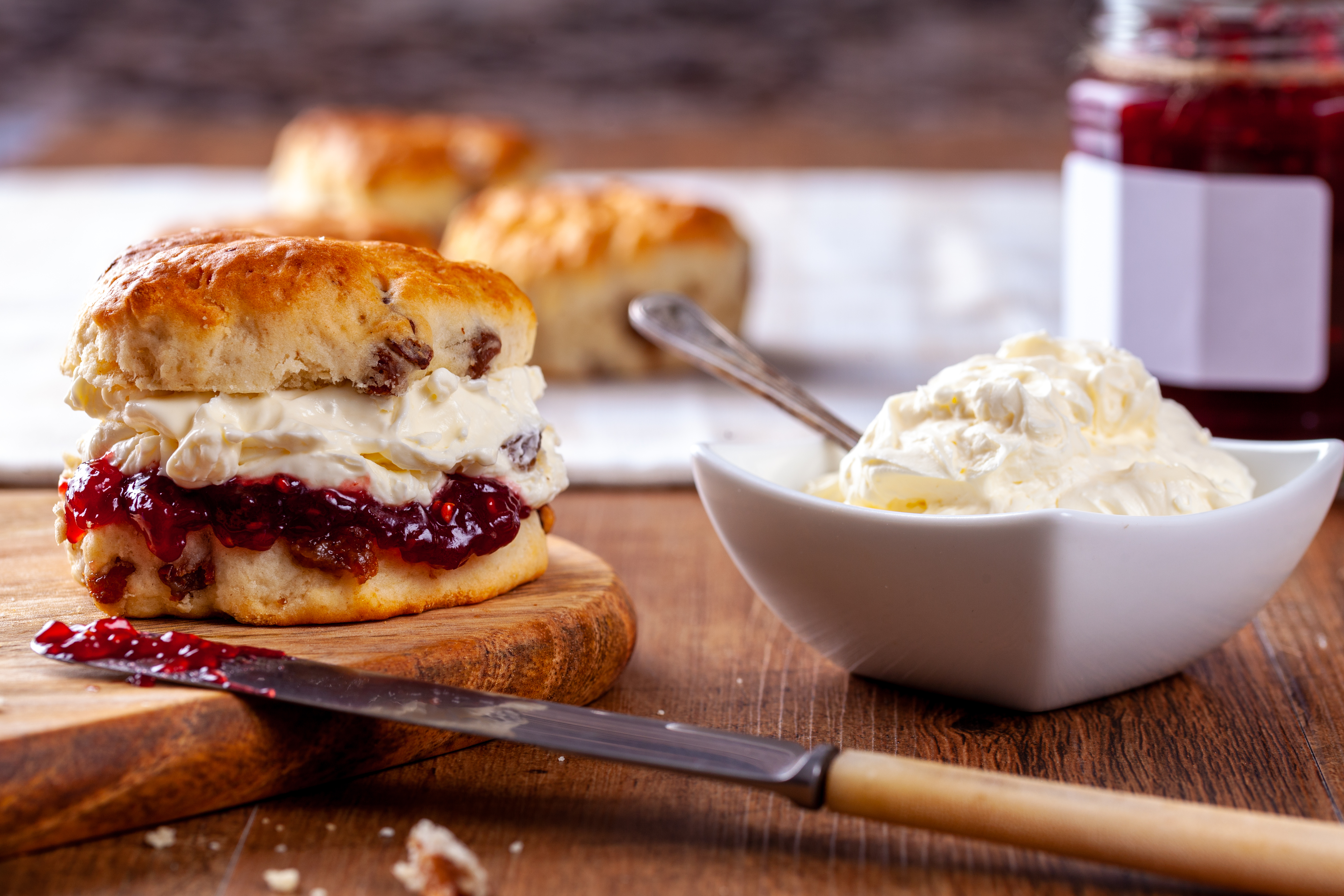 Traditionel engelsk cream tea med hjemmebagte scones, jordbærmarmelade og clotted cream fra Cornwall, serveret på hvid tallerken