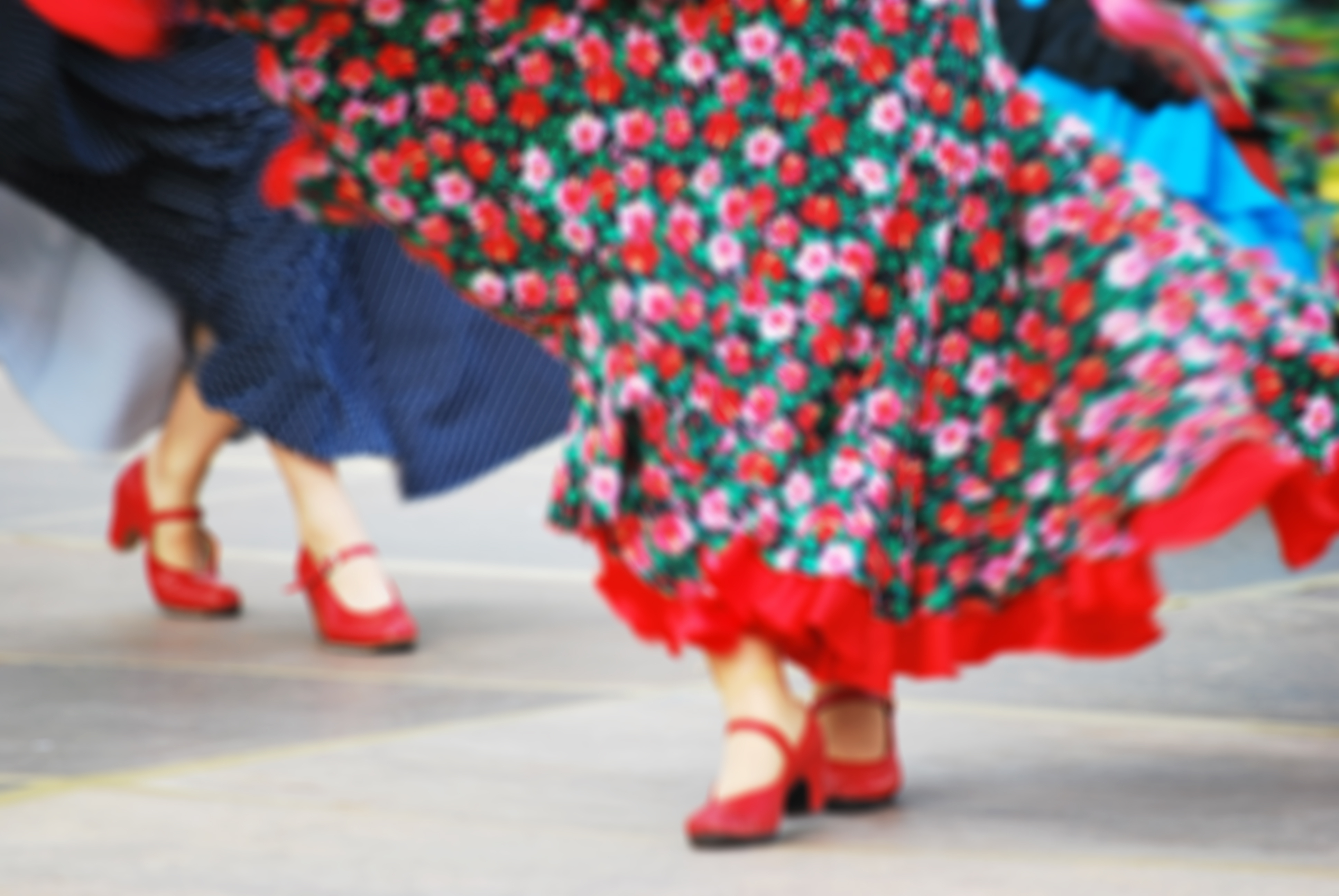 Traditionelle folkedansere i farverige blomstrede kjoler udfører kulturel dans med røde sko