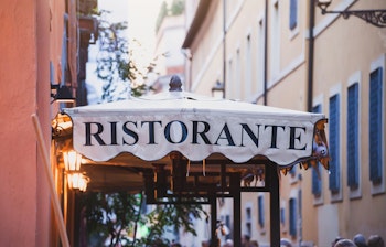 Charmerende italiensk restaurant med oplyst skilt i den historiske Trastevere-bydel i Rom, perfekt til en autentisk madoplevelse