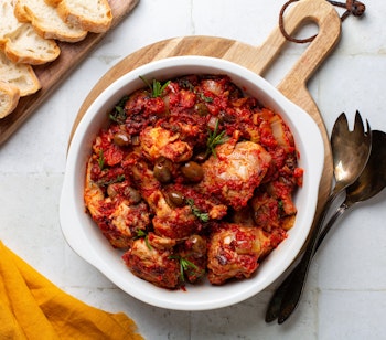 Traditionel kaninstuvning Coniglio all'ischitana fra Ischia i Italien, tilberedt med hvidvin, tomater, oliven og krydderurter, serveret med friskbagt brød