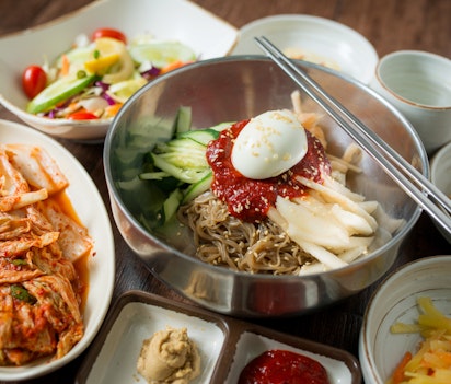 Traditionel koreansk bibimbap med kimchi og side-retter serveret i metalskåle på en restaurant i Seoul