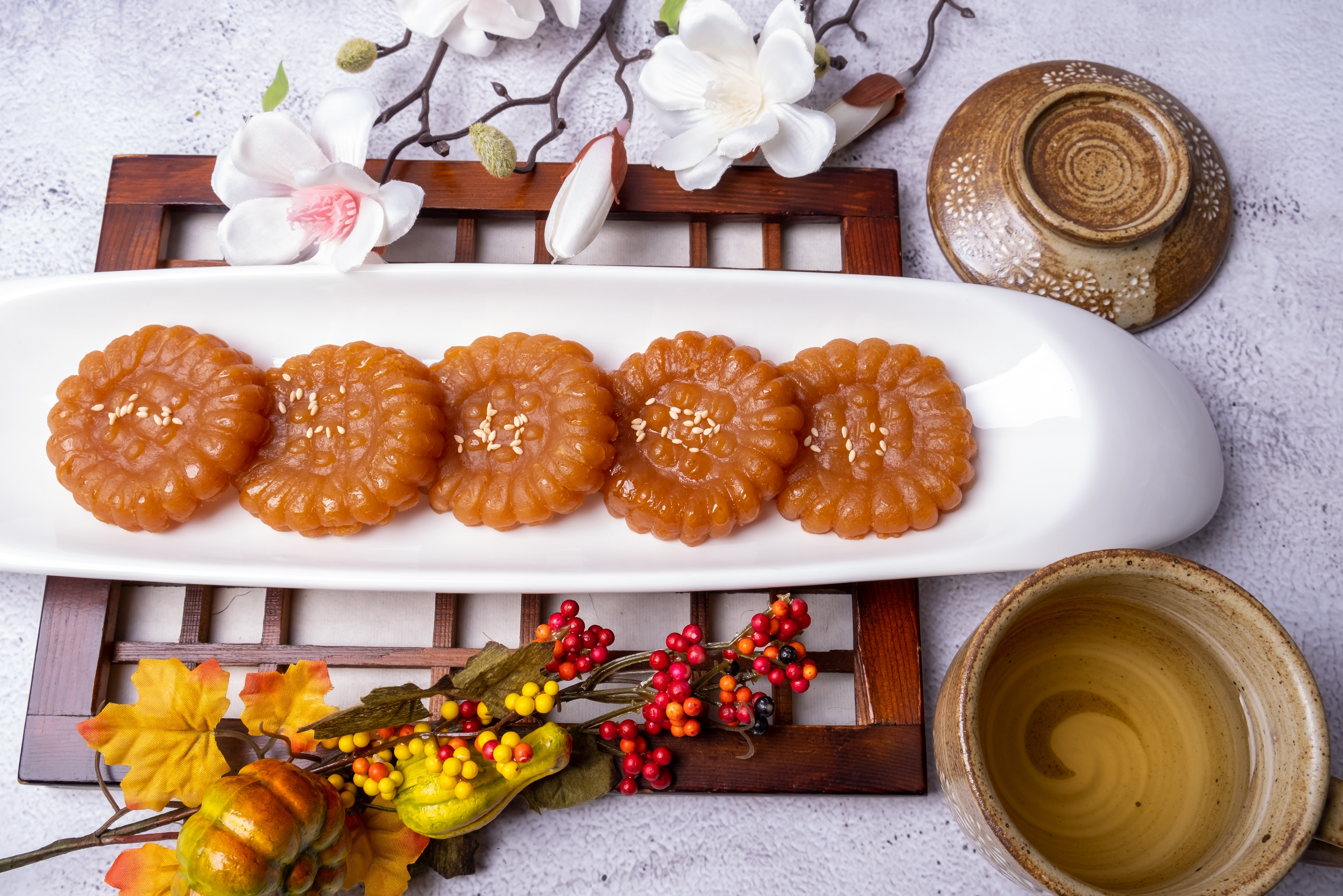 Traditionelle koreanske Yakgwa honningkager serveret på hvid tallerken med dekorative blomster og tedrikkeudstyr, en populær dessert under Chuseok-festivalen i Sydkorea