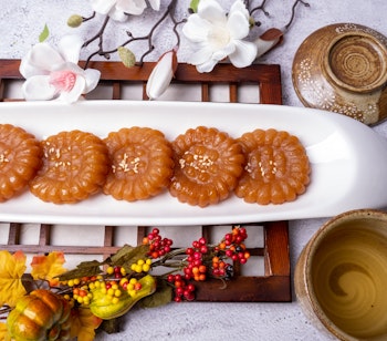 Traditionelle koreanske Yakgwa honningkager serveret på hvid tallerken med dekorative blomster og tedrikkeudstyr, en populær dessert under Chuseok-festivalen i Sydkorea