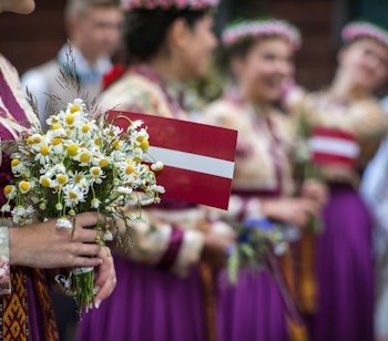 Farverige lettiske folkedansere i traditionelle dragter under sang- og dansefestivalen i Riga, en vigtig kulturel begivenhed i Letland