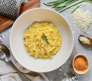 Traditionel safranrisotto fra Milano serveret i hvid tallerken med ris, ost og krydderier - en autentisk smagsprøve på Milanos kulinariske arv
