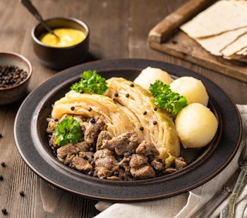 Traditionel norsk fårikål med mørt lammekød og kål, serveret med kartofler, sennep og fladbrød - en klassisk efterårsret