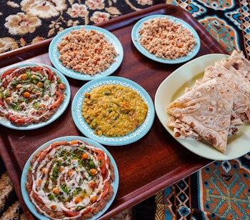 Traditionelle omanske retter serveret på farverigt tæppe i autentisk restaurant, viser den rige madkultur i Oman