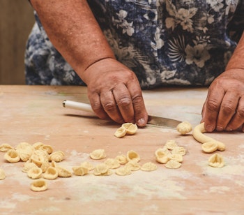Lokal kvinde fremstiller traditionel orecchiette pasta i Baris gamle bydel - en kulinarisk specialitet fra Puglia-regionen i Syditalien