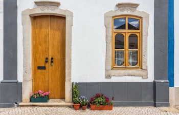 Charmerende hvidt hus med trævindue og dør i en historisk gade i Algarve, Portugal