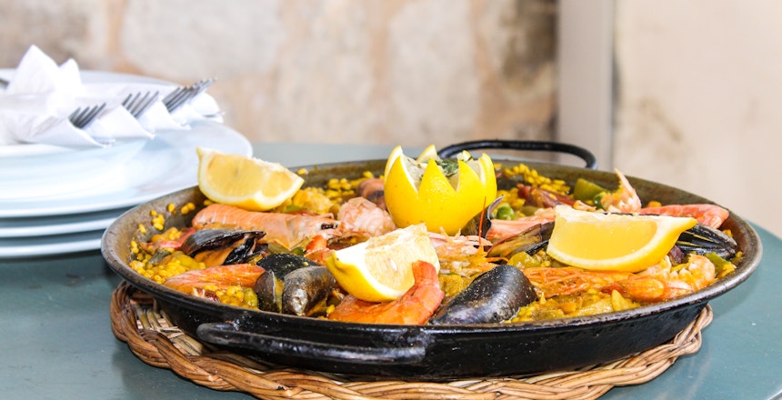 Autentisk spansk seafood paella serveret i strandrestaurant på Mallorca med muslinger og rejer