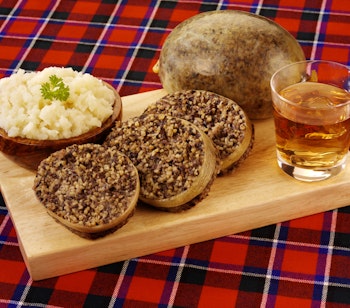 Traditionel skotsk haggis med neeps and tatties serveret på tartan dug til Burns Night fejring i Skotland