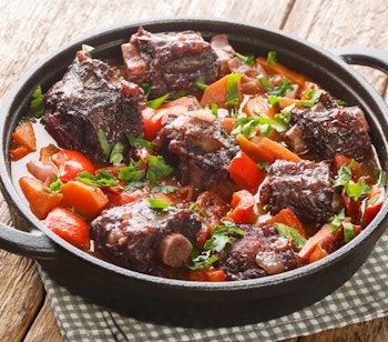 Traditionel spansk oksehaleragout (Rabo de Toro) i rødvinssauce serveret i en rustik gryde, autentisk andalusisk specialitet