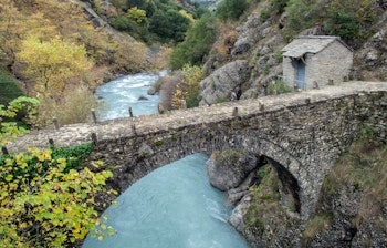 Historisk stenbro med bue i Epirus, Grækenland omgivet af frodige efterårsskove og dramatisk bjerglandskab