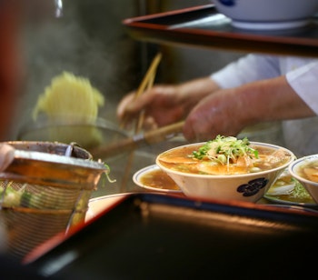 Farverig udstilling af frisk sushi og skaldyr ved en traditionel japansk madbod på Tsukiji Fiskemarkedet i Tokyo