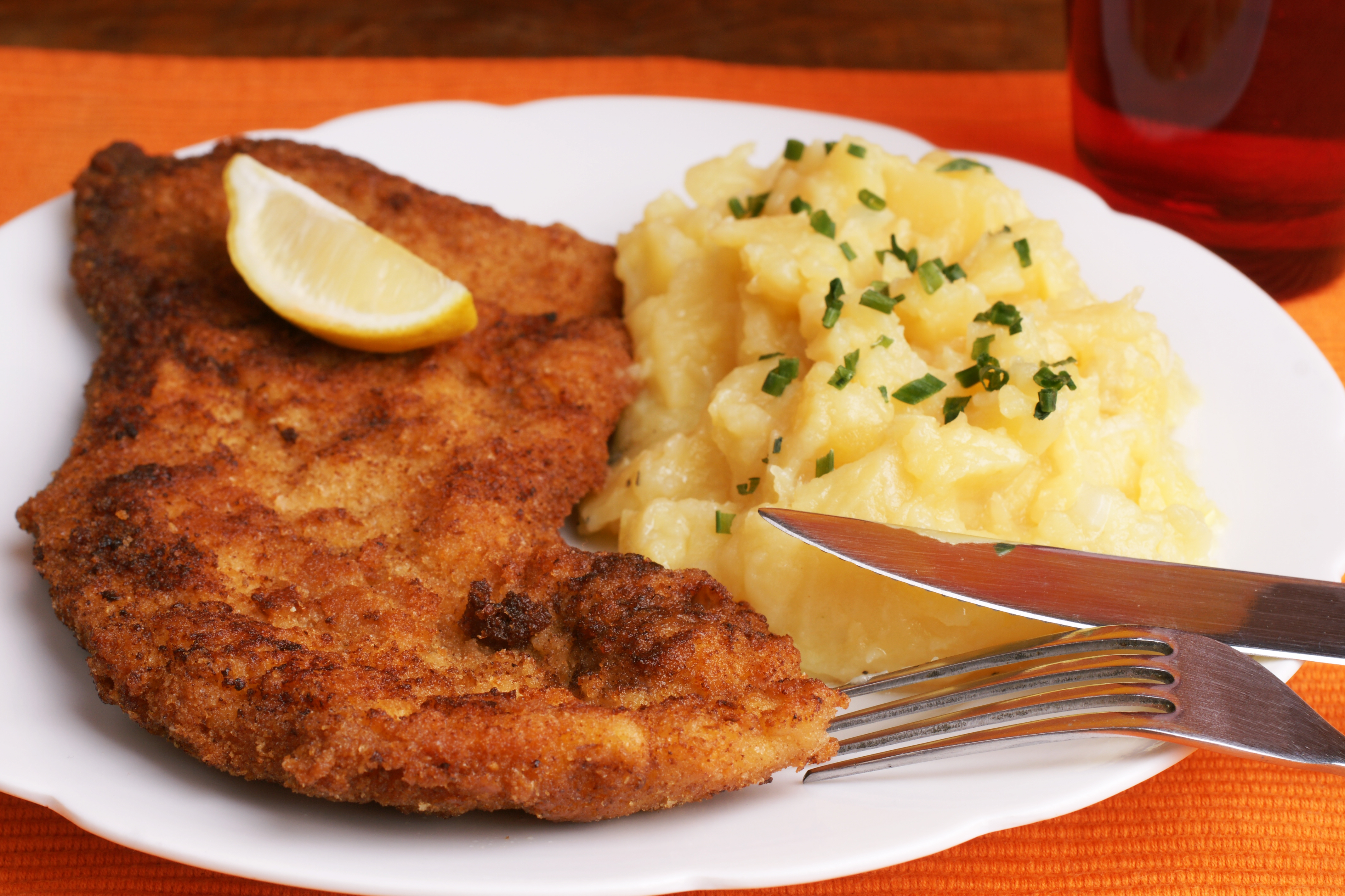 Klassisk Wiener Schnitzel serveret med kartoffelsalat og friske purløg, en østrigsk specialitet