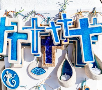 Farverige blå og hvide souvenirs fra Santorini med traditionelle græske kors og dekorative elementer, der afspejler øens unikke kultur og arkitektur