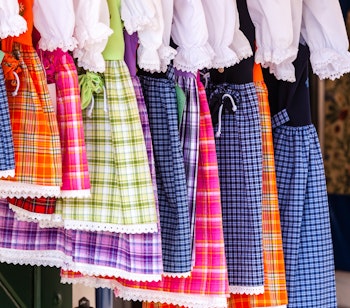 Traditionelle europæiske folkedragter med farverige ternede dirndl og hvide bluser hængende på tøjstativ