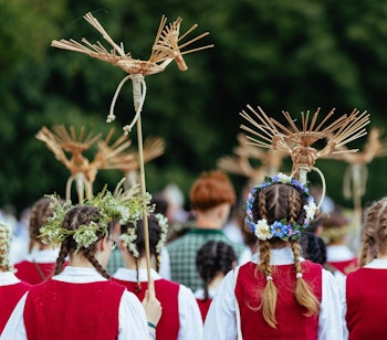 Litauisk kulturfestival med unge kvinder i traditionelle røde og hvide folkedragter med karakteristiske hovedbeklædninger i Vilnius