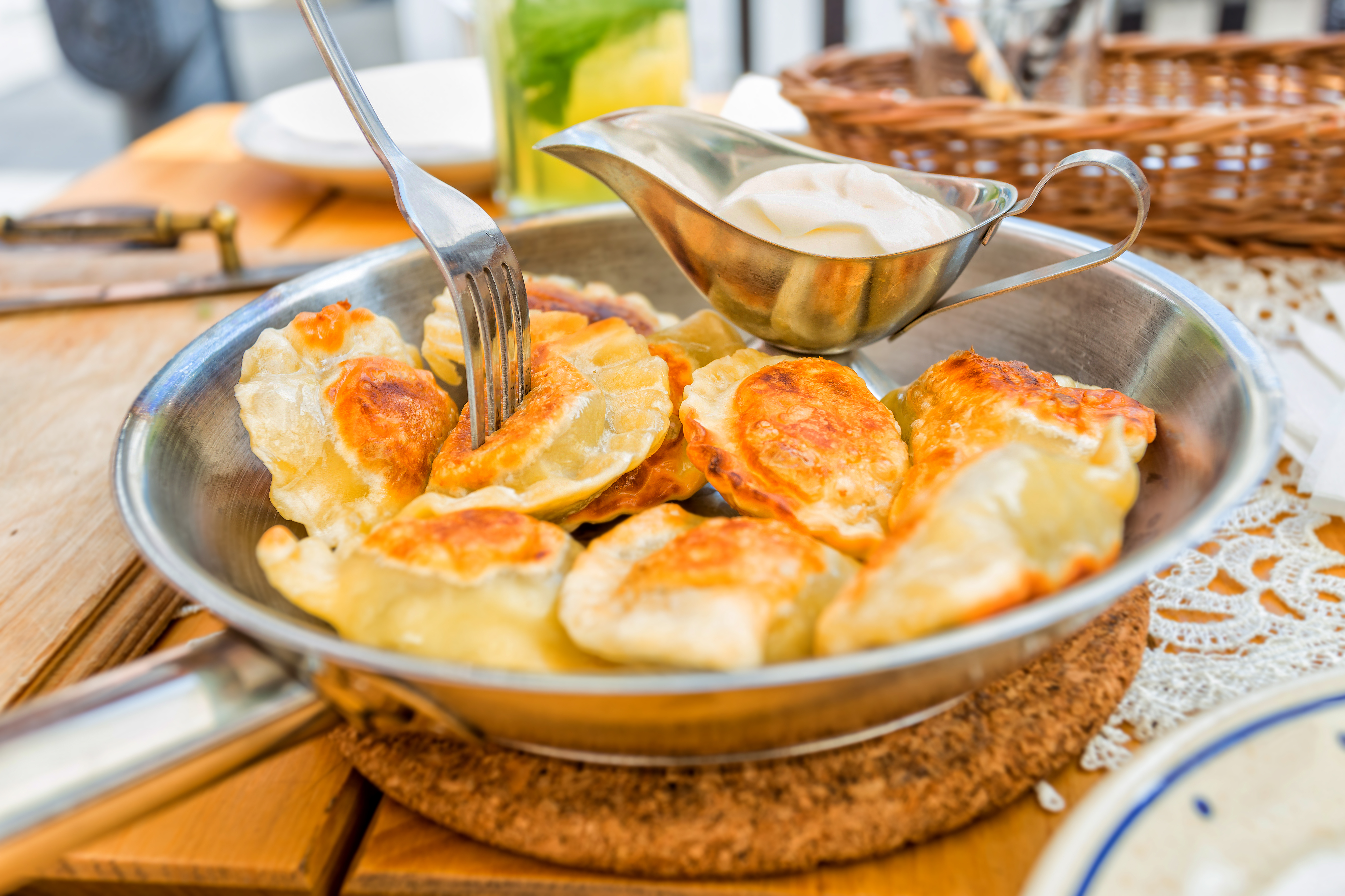 Traditionelle polske pierogi serveret med cremefraiche i rustik pande, autentisk polsk madkultur fra Krakow