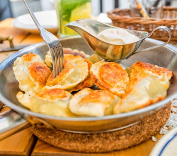 Traditionelle polske pierogi serveret med cremefraiche i rustik pande, autentisk polsk madkultur fra Krakow