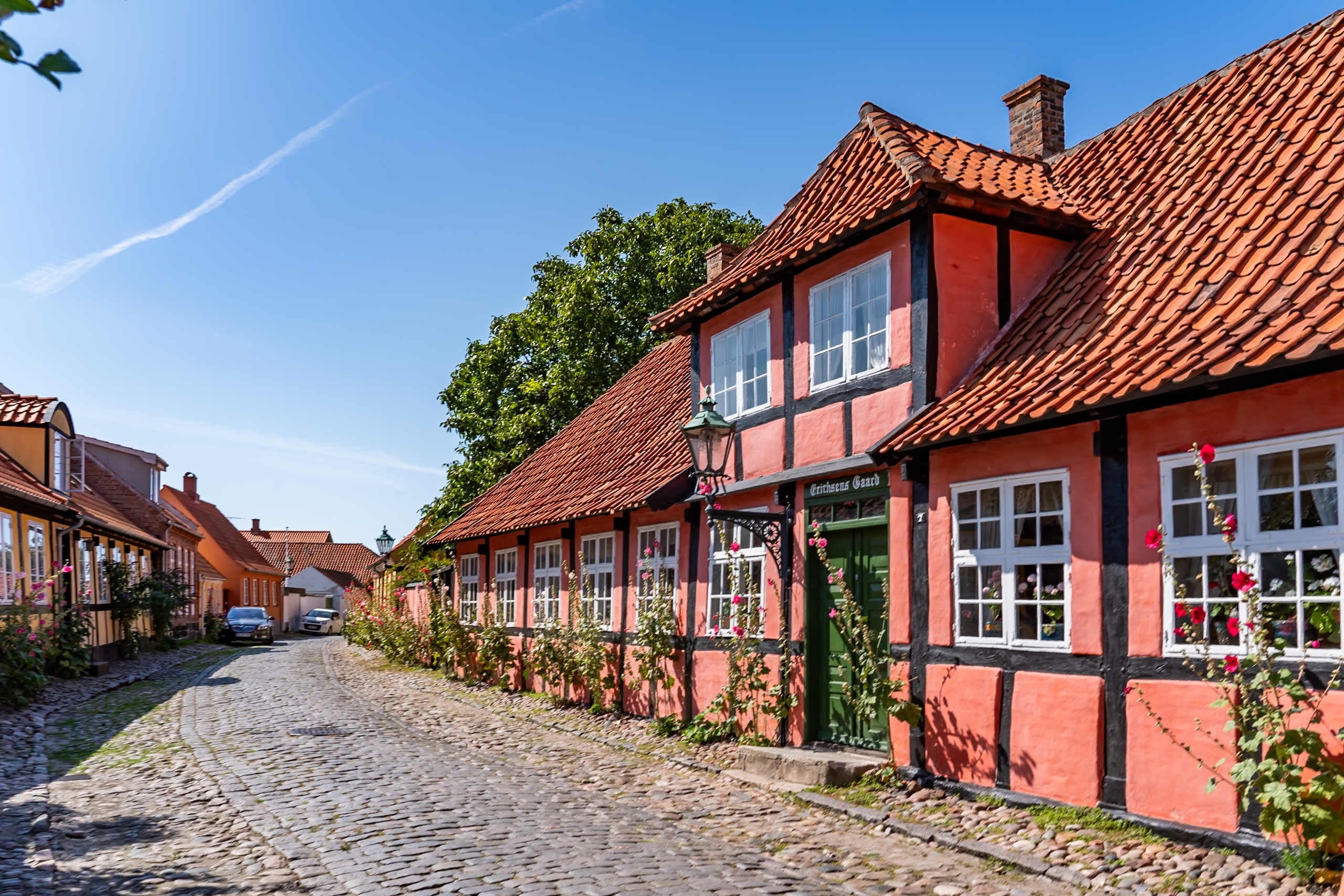 Traditionelle røde bindingsværkshuse langs brolagt gade i historisk dansk landsby