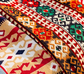 Farverigt traditionelt albansk uldtæppe med geometriske mønstre håndvævet og udstillet på marked i Albanien