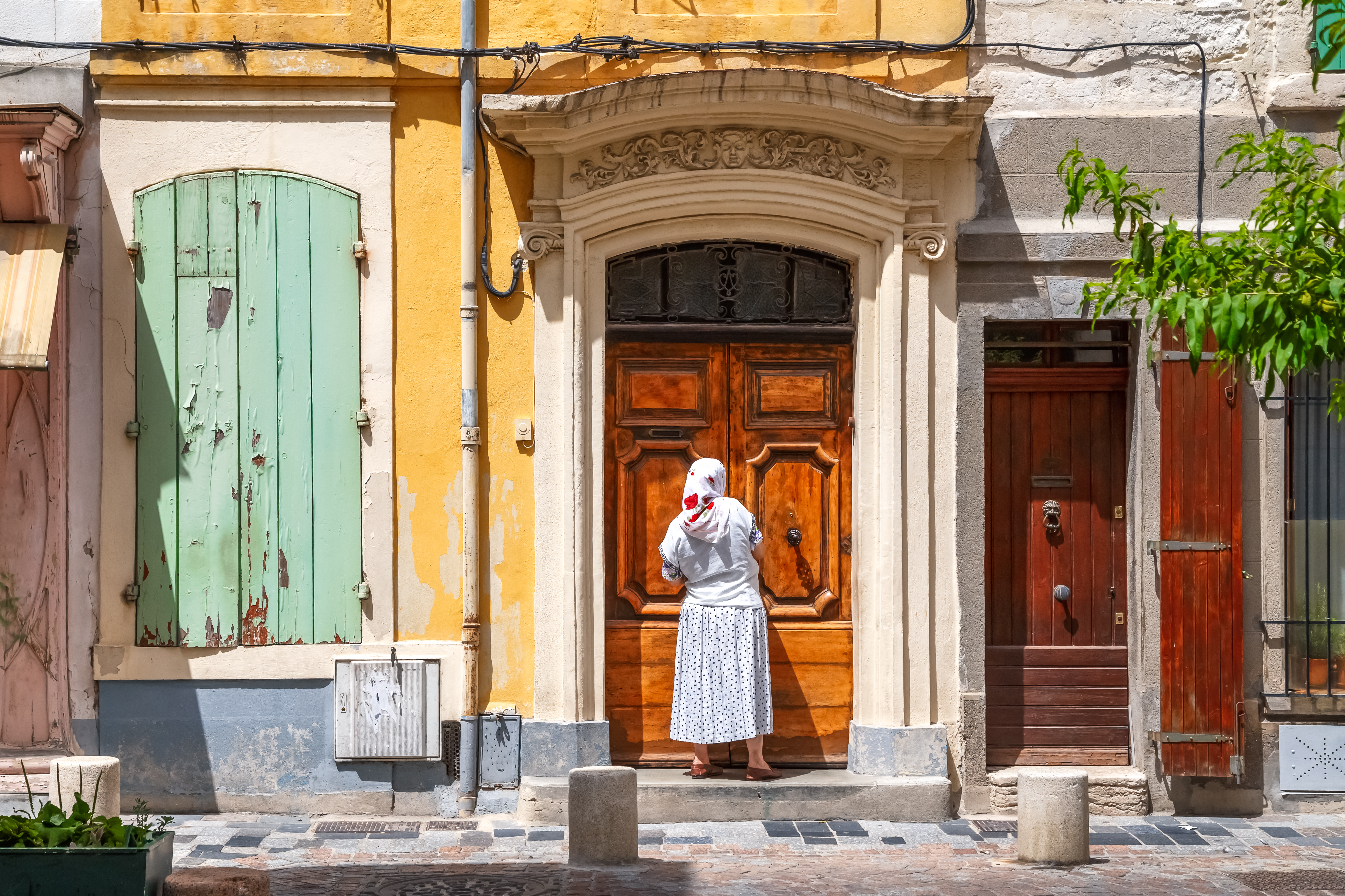 Traditionelt stenhus med grønne træskodder og udskåret døråbning i historiske Arles, Provence, Frankrig